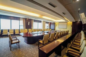 Un salón de conferencias con una larga mesa, varias sillas y una pantalla grande.