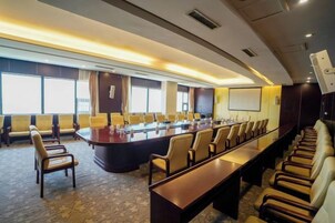 A conference room with a long table, multiple chairs, and a large screen.
