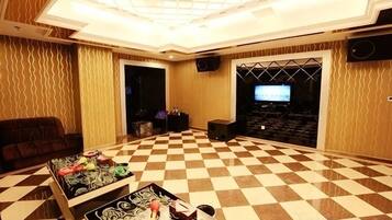 A spacious room with a checkered floor, a sofa, a coffee table with items, and a television.