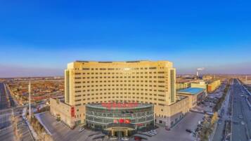 A large hotel with a central circular atrium, multiple floors, and a parking area.