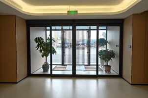 A hotel lobby with a large sliding glass door, potted plants, and a clean, modern interior.