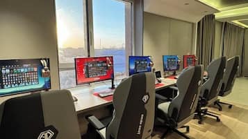 Ein Konferenzraum mit mehreren Monitoren, Gaming-Stühlen und Blick auf die Stadt.