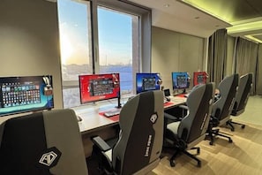 A conference room with multiple monitors, gaming chairs, and a city view. - Shu Mei Business Hotel (Panjin)