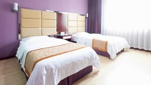 Quarto de hotel com duas camas, uma cabeceira grande e uma janela com cortinas.