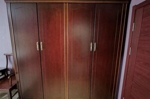 A large wooden wardrobe with two doors and a mirrored closet door.