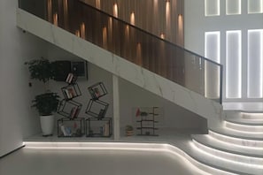 Un escalier avec une rampe en bois, une plante en pot et des livres disposés sur une étagère.
