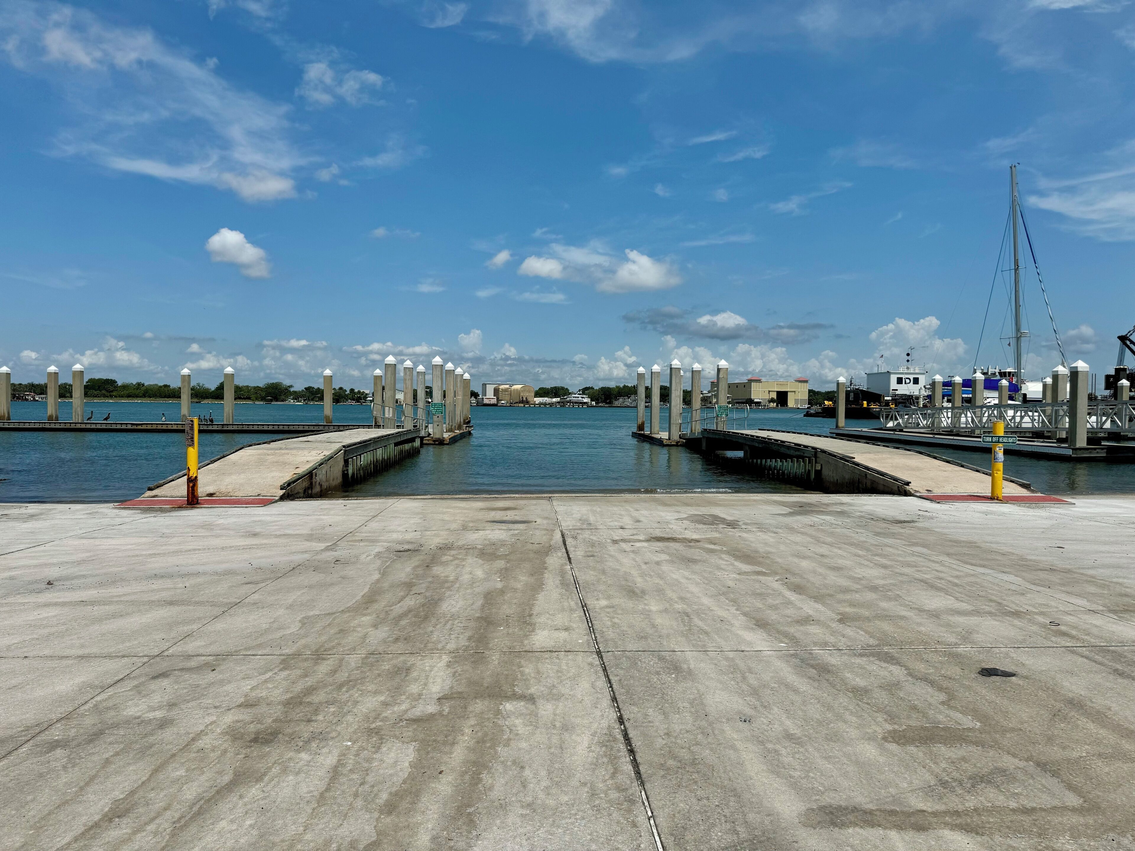 A marina with concrete docks and bollards, calm water, and a clear sky.