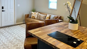 A modern kitchen with a wooden countertop, a built-in stove, and a white cabinet. - 1BR Modern Bungalow close to Fishing, Navy Base and Ocean (Jacksonville)
