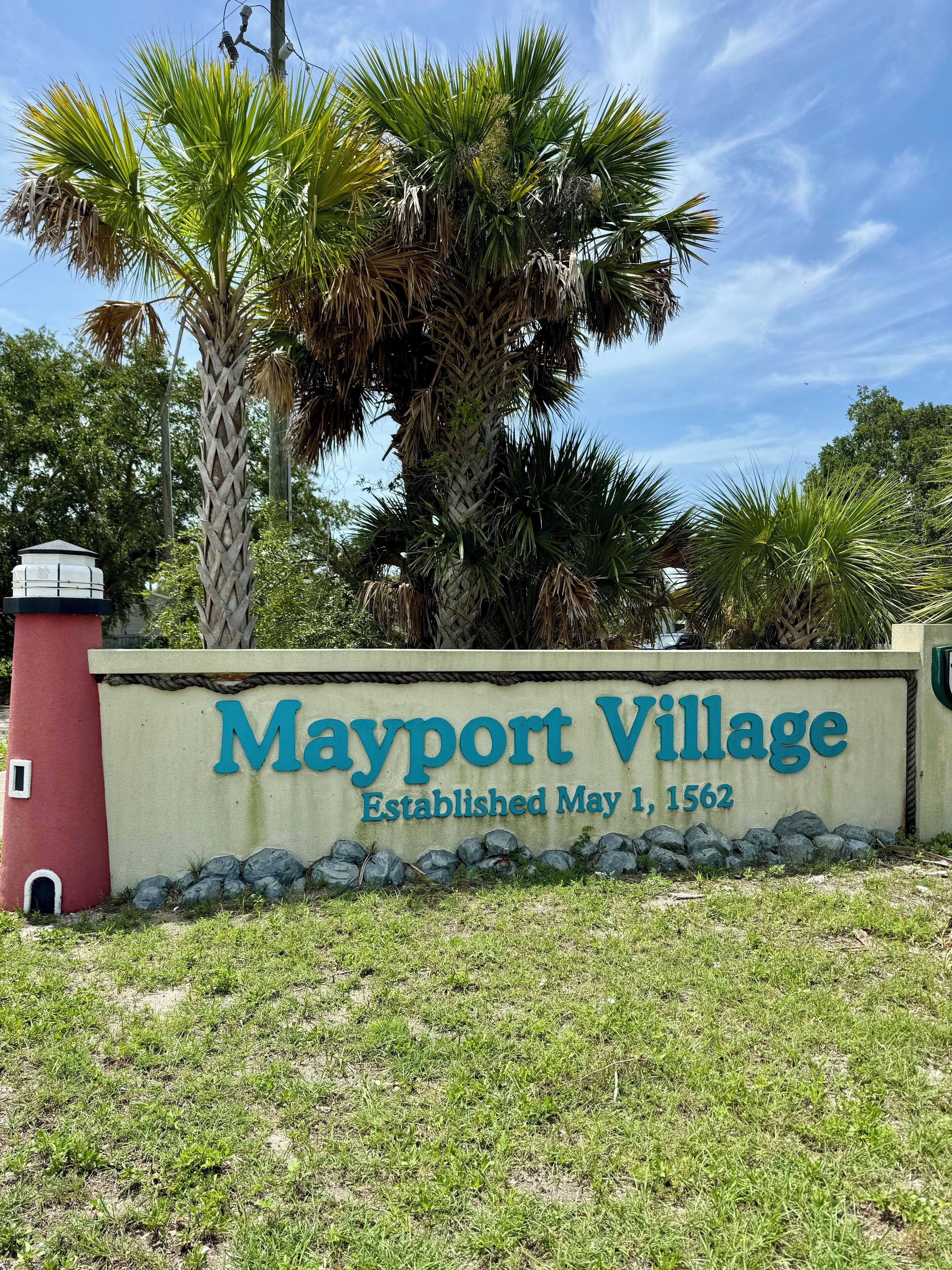 A sign for Mayport Village with a lighthouse and palm trees.