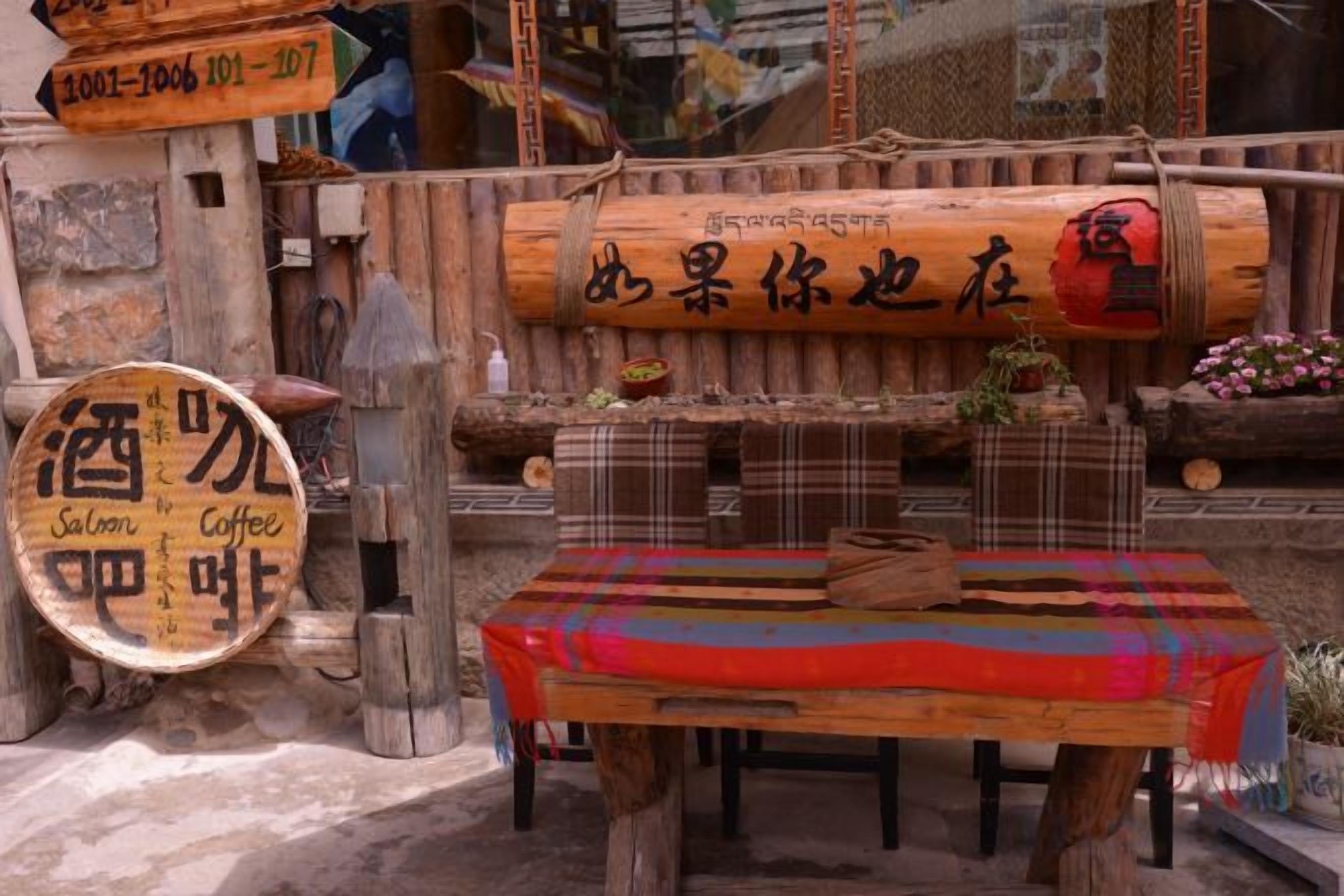 A rustic wooden table with a plaid tablecloth, surrounded by wooden stools and a sign indicating a coffee and saloon.