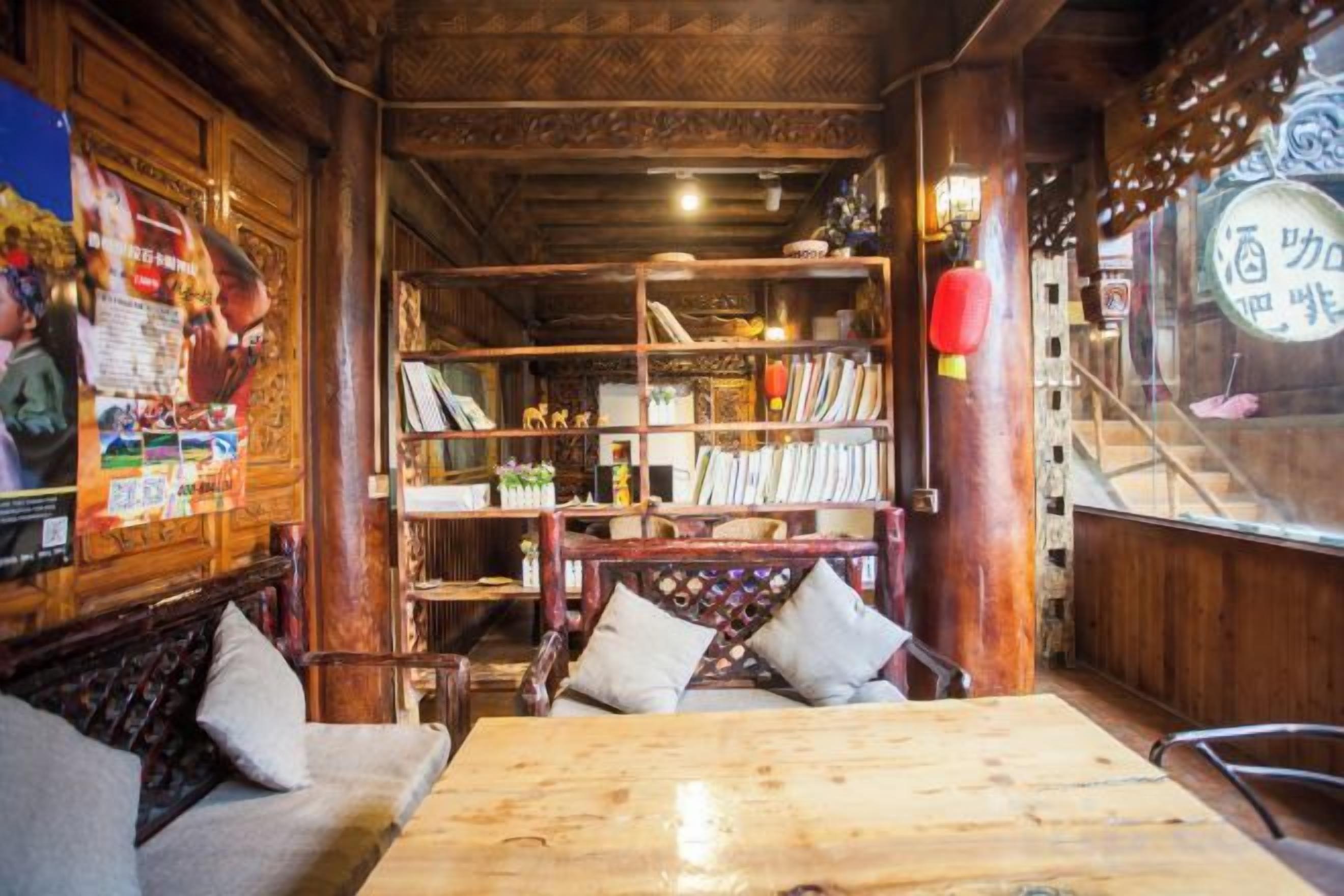 A traditional wooden interior with a wooden table and benches, a bookshelf, and a decorative lantern.