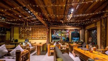 A cozy wooden interior with string lights, wooden furniture, and a bar area.