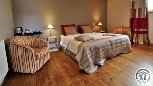 A bedroom with a bed, a striped armchair, a nightstand, and a lamp. - Gîte "domaine Gilles Coperet" (REGNIE DURETTE)