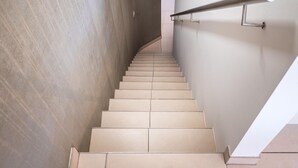 Eine moderne Treppe mit beigefarbenen Fliesen und einem Metallgeländer, die zu einer höheren Etage führt.