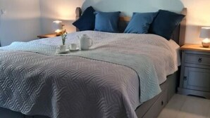 A neatly made bed with a white and grey quilt, a bedside table with a lamp, and a wall-mounted artwork. - Garden Magic Comfortable Holiday Residence (Goch)