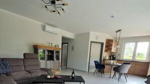 A spacious living area with a sofa, coffee table, and a dining area with chairs and a table. - Garden Magic Comfortable Holiday Residence (Goch)