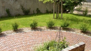 A circular brick patio with a central planter and a tree in the background. - Holiday Apartment Tannenhof Bornholdt (Lutzhorn)