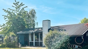 A house with a chimney, a screened porch, and a grassy yard. - 4 Person Holiday Home in Frorup (Frørup)