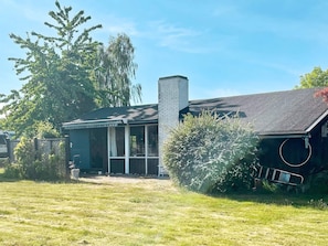 A house with a chimney, a screened porch, and a grassy yard.