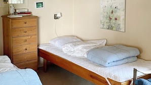 A bedroom with a wooden bed, a wooden dresser, and a wall-mounted lamp. - 4 Person Holiday Home in Frorup (Frørup)