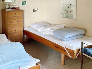 Un dormitorio con una cama de madera, un aparador de madera y una lámpara fijada a la pared.