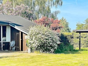 A wooden cabin with a covered porch and a fenced yard. - 4 Person Holiday Home in Frorup (Frørup)
