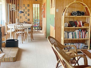 A cozy room with a round dining table, chairs, a bookshelf, and a wicker chair. - 4 Person Holiday Home in Frorup (Frørup)