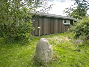 Un bâtiment en bois portant le numéro « 2 », entouré de verdure et avec un grand rocher au premier plan.