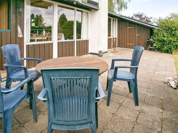 A patio area with a round wooden table and four blue chairs.