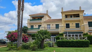 A two-story building with a tiled roof, balconies with decorative railings, and a well-maintained garden with palm trees and bougainvillea. - Bungalow in Ayamonte Near Portugal Border (Ayamonte)