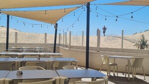 An outdoor dining area with tables and chairs, string lights, and a view of the beach. - Bungalow in Ayamonte Near Portugal Border (Ayamonte)
