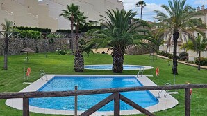 A swimming pool with a wooden fence, surrounded by palm trees and a well-maintained lawn. - Bungalow in Ayamonte Near Portugal Border (Ayamonte)