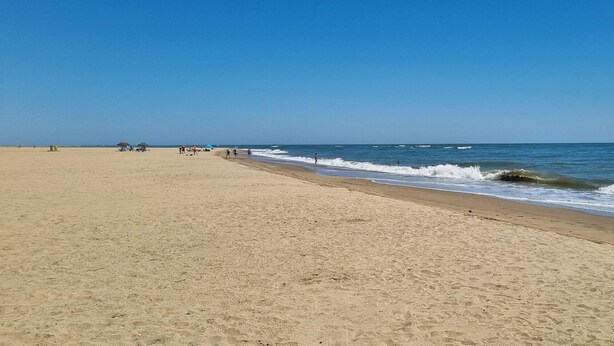 A wide sandy beach with gentle waves and a clear blue sky. - Bungalow in Ayamonte Near Portugal Border (Ayamonte)