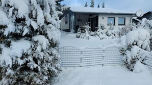 A snow-covered house with a visible garage door and a satellite dish. - Holiday Home Kent Comfortable Vacation Home (Willingen)