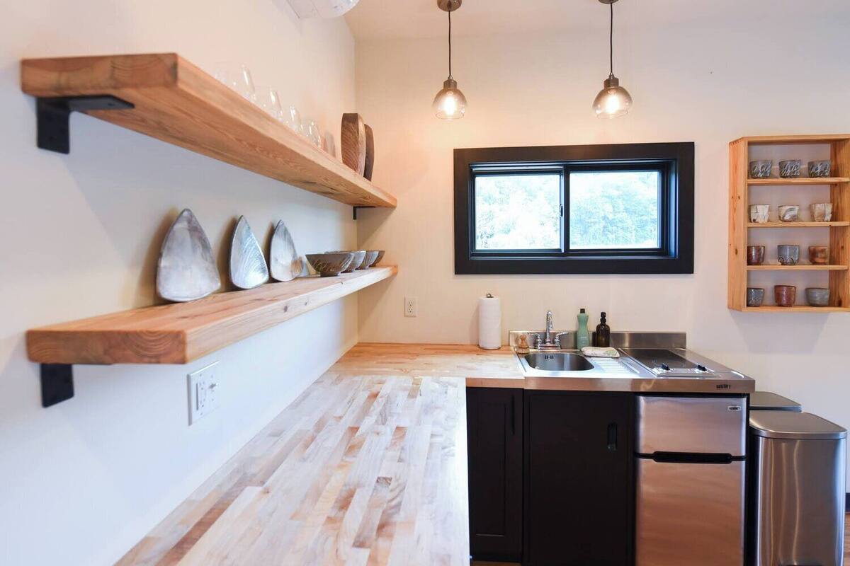 A modern kitchen with wooden shelves, a window, and stainless steel appliances.