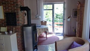 Uma sala de estar aconchegante com lareira, uma área de jantar e uma cadeira de vime.