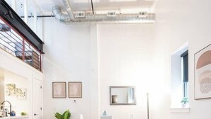 A modern living room with a grey sofa, a round coffee table, and a bookshelf. - Classic Loft King Bed 30 min NYC (East Orange)