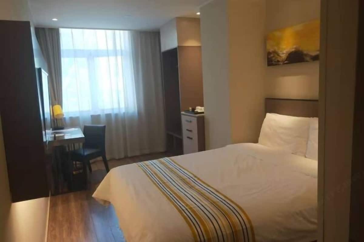 A hotel room with a bed, a desk, and a chair.