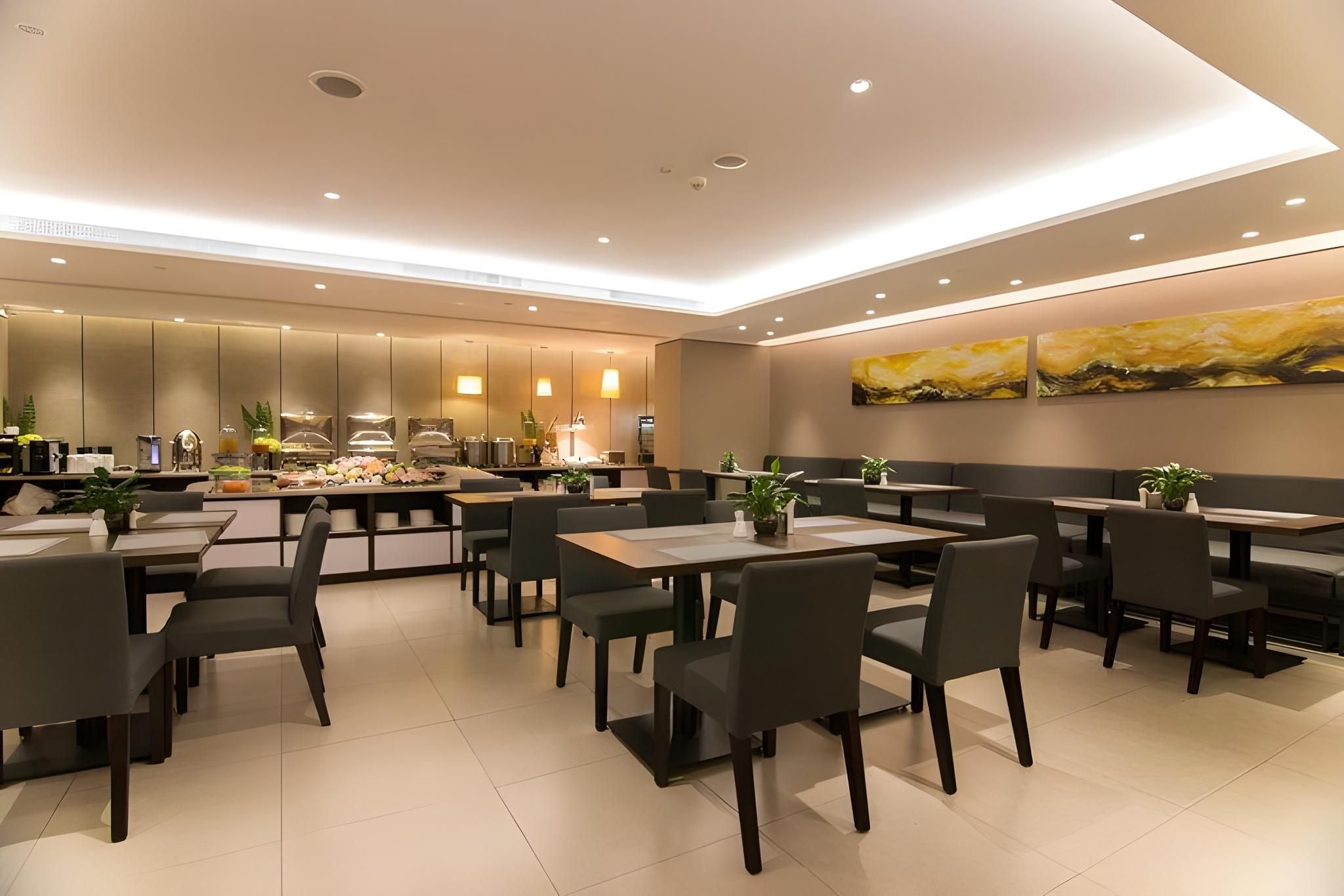 A modern restaurant with a central bar area, multiple seating options including booths and tables, and a minimalist decor with neutral colors.
