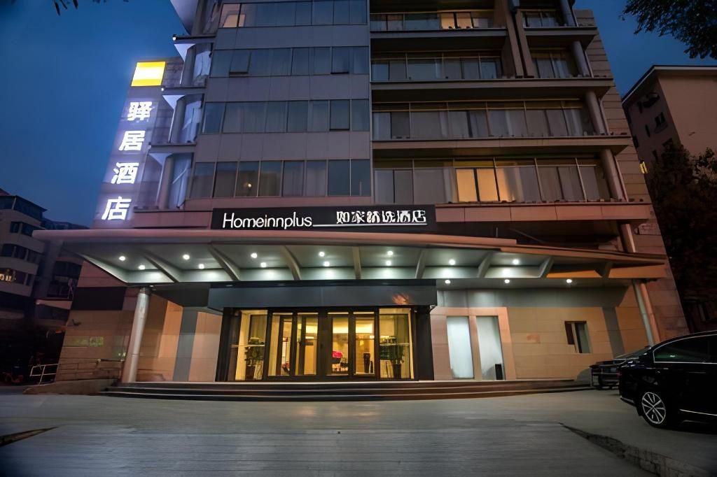 Entrada de un hotel con un corredor techado y un letrero que indica 'Homeinnplus' y 'Homeinn Hotel'.