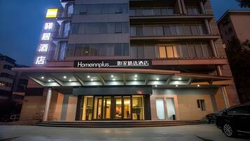 Entrada de un hotel con un corredor techado y un letrero que indica 'Homeinnplus' y 'Homeinn Hotel'.