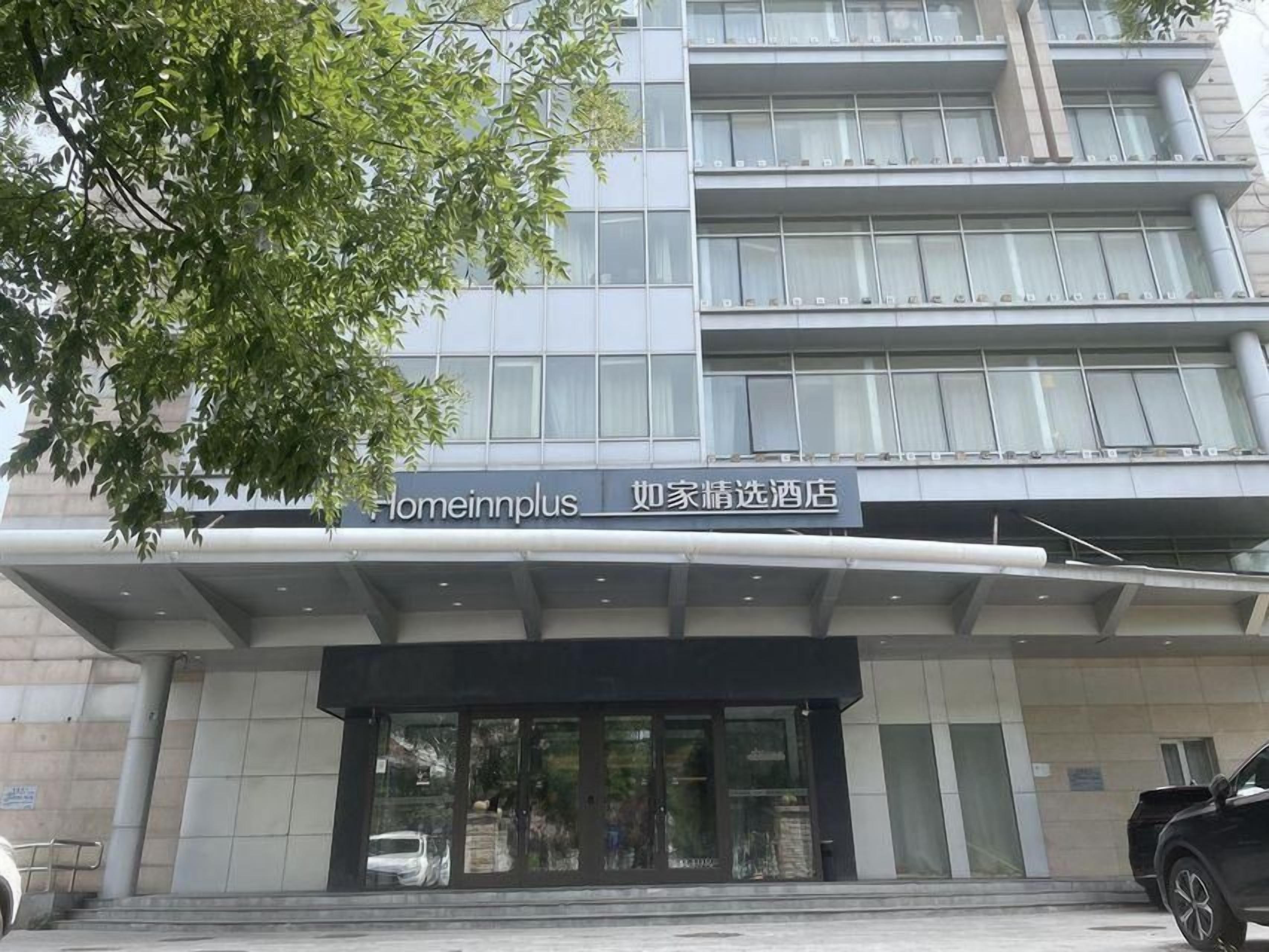 A hotel entrance with a sign indicating 'Homeinnplus' and 'Homeinnplus Select Hotel'.