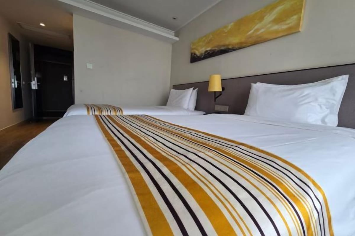 Ein Hotelzimmer mit einem großen Bett, einem Kopfteil mit Lampe und einem Bild an der Wand.