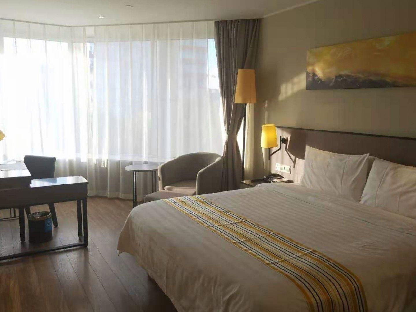 Una habitación de hotel con una cama grande, un escritorio, una silla y una lámpara.