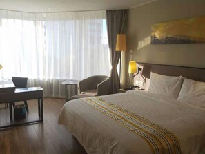 Ein Hotelzimmer mit einem großen Bett, einem Schreibtisch, einem Stuhl und einer Lampe.