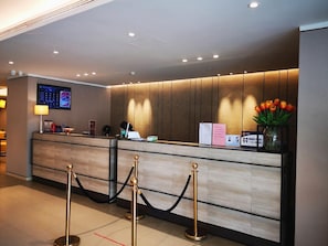 A hotel reception desk with a digital display, a reception counter, and a vase of flowers. - Homeinn Plus Hotel (Beijing Zhongguancun East Road) (Beijing)