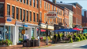 A street view with a brick building housing a soda shop and a clothing store.