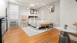 A modern Nordic suite with a bed, bedside table, chair, and a small table with a plant.