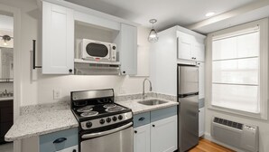 A kitchen with white cabinets, a stainless steel stove, a microwave, and a refrigerator.