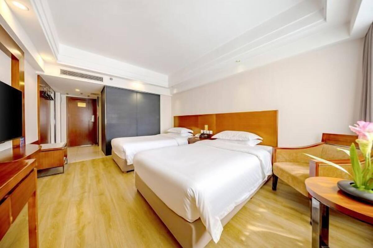 A hotel room with two beds, a TV, a desk, and a chair.